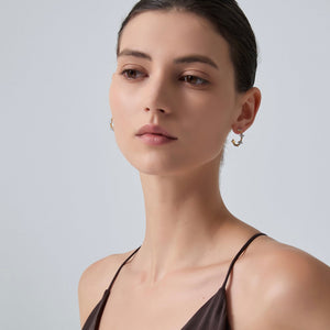 Woman wearing a black strappy top against a plain background