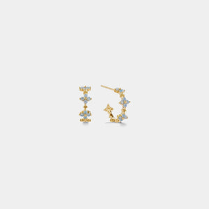 Pair of gold earrings with blue gemstones on a light gray background