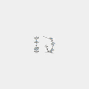 Pair of silver earrings with gemstones on a light gray background