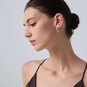 Woman wearing a delicate earring on a plain background