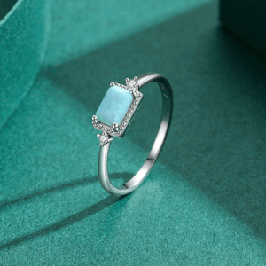 Silver ring with a turquoise gemstone on a green fabric background
