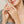 Close-up of a woman's hands with checkered sleeves, wearing rings on her fingers.