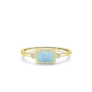 Gold ring with a blue gemstone and diamonds on a white background