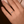 Close-up of a hand wearing a ring with a blue gemstone on a dark background