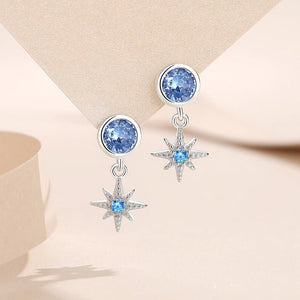 Silver earrings with blue gemstones on a beige background