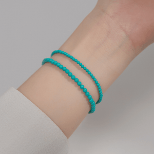 Turquoise beaded bracelet on a wrist against a neutral background