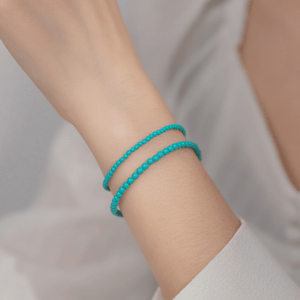 Turquoise beaded bracelet on a person's wrist against a neutral background