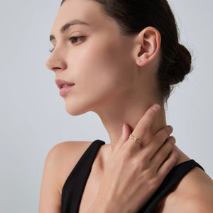 Woman wearing a gold ring on a plain background