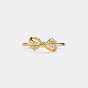 Gold bow-shaped ring with small diamonds on a light gray background