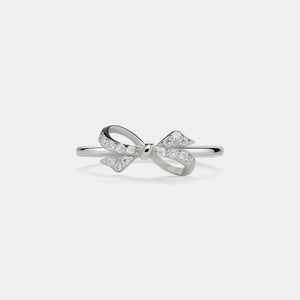 Silver bow-shaped ring with small diamonds on a light gray background