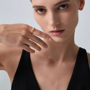 Woman wearing a gold ring on her finger against a neutral background