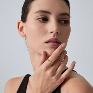 Woman wearing a gold ring on a plain background