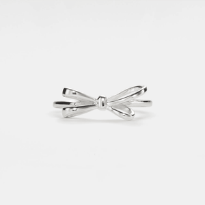 A gold-colored bow tie stacking band ring on a white background