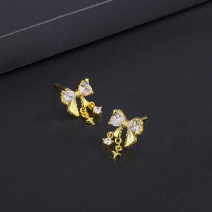 Gold bow-shaped earrings with clear gemstones on a black background