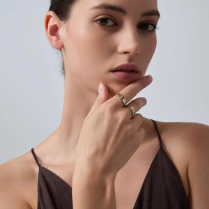 Woman wearing gold rings on a plain background