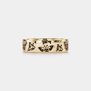 Gold ring with butterfly designs on a white background