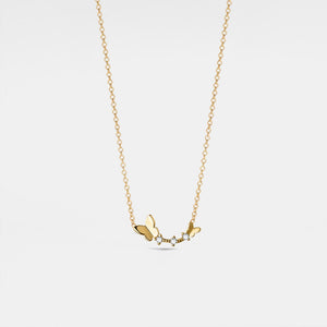Gold necklace with butterfly pendant on a light gray background