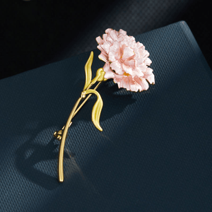 Pink flower brooch with gold stem on a dark blue background