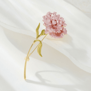 Pink flower brooch with gold stem on a white background
