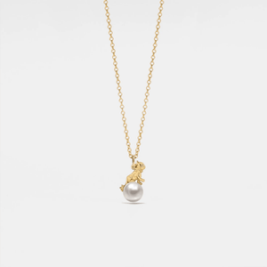 Gold necklace with a pearl pendant on a light gray background
