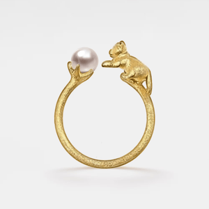 Gold ring with a bear and pearl design on a white background