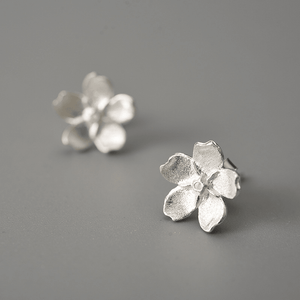 Silver flower-shaped earrings on a gray background
