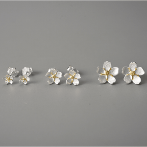 Flower-shaped earrings on a gray background