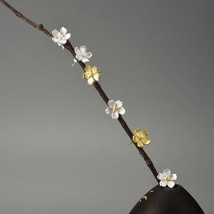 Decorative branch with gold and silver floral elements on a gray background