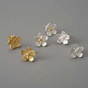 Gold and silver flower-shaped earrings on a gray background
