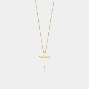 Gold cross necklace on a light gray background