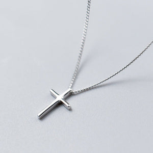 Silver cross necklace on a light gray background