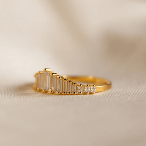 Gold ring with baguette-cut diamonds on a beige background