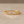 Gold ring with emerald-cut diamonds on a beige background