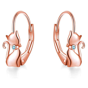 A pair of sterling silver hoop earrings with a cat face design, placed against a blue and white background.