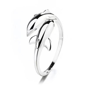 Silver ring with dolphin design on a white background