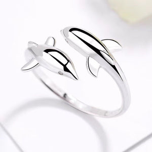 Silver dolphin-shaped ring on a reflective surface