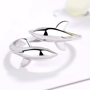 Two silver dolphin-shaped objects on a white surface