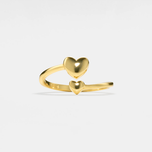 Gold heart-shaped ring on a light gray background