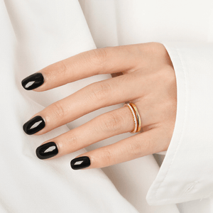 Hand with black nail polish and a gold ring on a white background