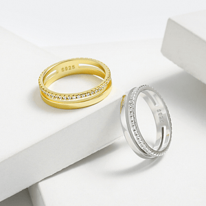Two gold and silver rings with diamond accents on a white surface