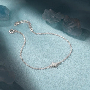 Silver bracelet with a star charm on a light blue fabric background