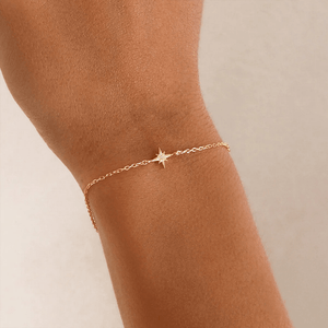 Gold star anklet on a person's ankle against a neutral background