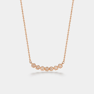 Rose gold necklace with small diamonds on a light gray background