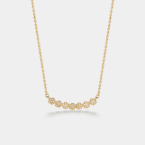 Gold necklace with a floral pendant on a light gray background