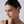 Close-up of a woman wearing a diamond earring against a neutral background