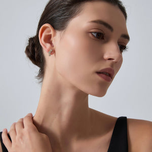 Close-up of a woman wearing a delicate earring against a neutral background