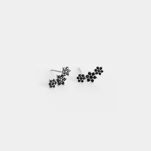 Pair of black floral stud earrings on a white background