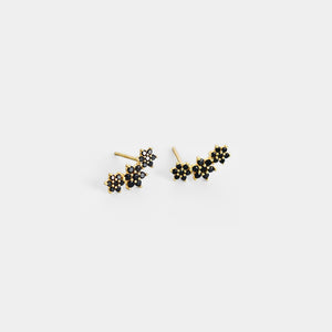 Pair of gold and black stud earrings on a white background