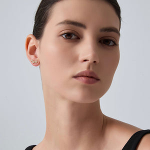 Close-up of a woman wearing a gold earring against a plain background