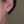 Close-up of a silver dragonfly earring worn on an ear with a plain background